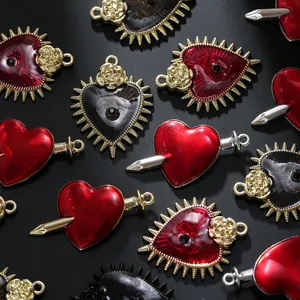 Macro shot of gothic heart and dagger alloy pendants with red oil drip and gold plating