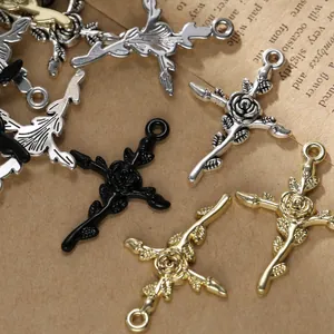 Vue macro de breloques croix rose en or, argent et noir pour la création de bijoux DIY