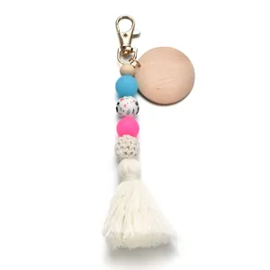 Détail de porte-clés en perles de silicone avec pompon blanc et étiquette en bois ronde