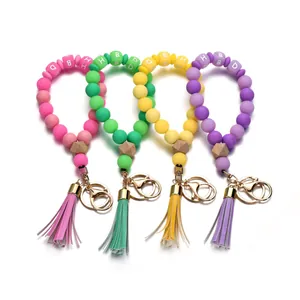 Porte-clés en perles de silicone lumineux avec charm en bois et pompons colorés en quatre tons