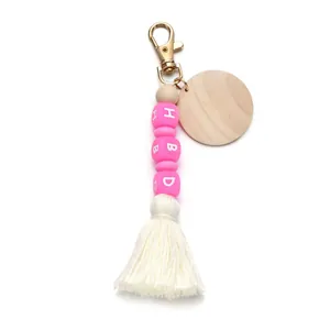 Detail view of pink silicone HBD beads with a natural wood disc and white cotton tassel