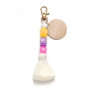 Detail of beaded keychain with multi-color HBD letter beads and white cotton tassel