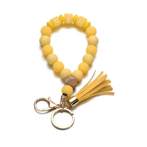 Détail de perles en silicone jaune avec touches de bois et breloques HBD sur porte-clés