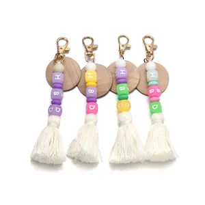 Close-up of four silicone bead keychains with HBD letters, wood discs and cotton tassels