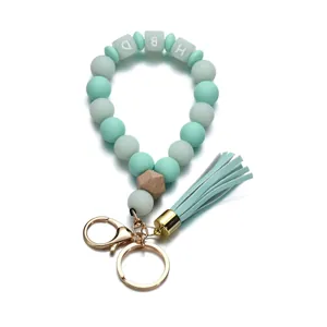 Détail du porte-clés perlé avec perles HBD, pompon vert et fermoir doré mousqueton