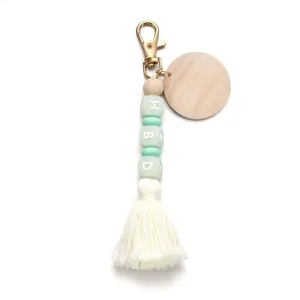 Silicone bead keychain with mint green colors, wooden disc, and white cotton tassel