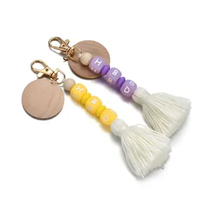 Detail of silicone HBD bead keychain with wooden disc and soft tassel fringe