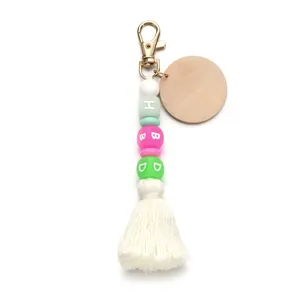 Macro detail of silicone beads with HBD letters, wood disc and white tassel keychain