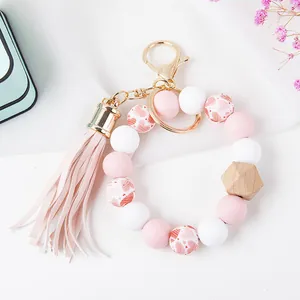 Detail of pink silicone beads, wooden accent, and leather tassel on a gold keychain ring