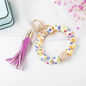 Detail of floral beads bracelet keychain with purple leather tassel and golden hardware