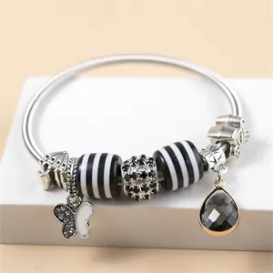 Bedelarmband met vlinderhanger, gestreepte kralen en donkergrijze druppelvormige steen