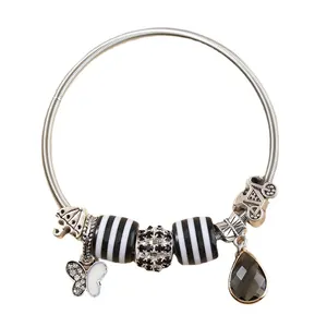 DIY bedelarmband met vlinder, fiets en zwart gestreepte kralen op zilveren elastiek band