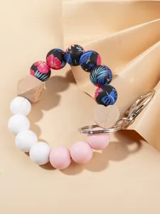 Detalle de pulsera de cuentas de silicona floral con placa de corazón y llavero