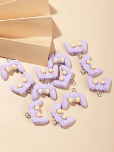 Macro shot of purple resin game controller charms with yellow buttons and metal eyelets