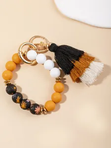 Detail of bohemian silicone bead bracelet with daisy patterns and tri-color tassel charm
