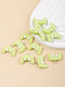 Detailed macro view of ten light green resin gamepad charms on a white embossed plate
