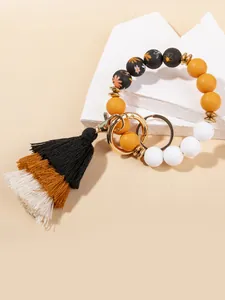 Detail of bohemian silicone bead wristlet with yellow beads and cotton tassel