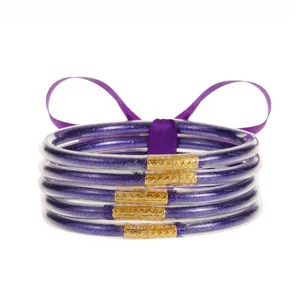 Detalle de 5 pulseras de silicona con purpurina morada y cierre de metal dorado