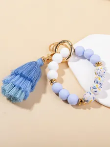 Detail of light blue and floral silicone bead bracelet with navy blue tassel and gold hardware