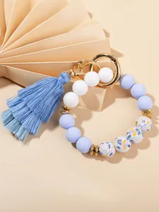 Detail of floral printed silicone beads and blue tassel on a golden spring ring keychain