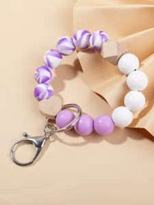Detalle de pulsera llavero con cuentas de silicona moradas y colgante de corazón de madera