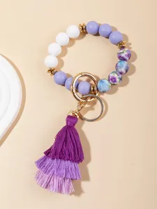 Detail of beaded tassel keychain bracelet with purple floral patterns and golden clasp