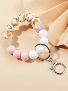 Detalle de pulsera llavero con cuentas de madera y patrón de frutas naranja