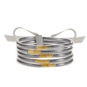 Primer plano de cinco pulseras de silicona con purpurina y cierres metálicos dorados