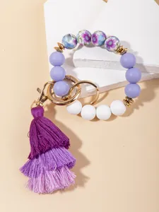 Detail of purple floral silicone beads, golden keychain ring and multi-layer tassel