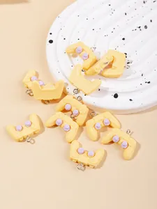Macro detail of yellow resin game controller charms with purple buttons for DIY crafts