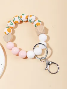 Detalle del llavero de pulsera con cuentas de silicona florales y corazón de madera