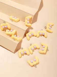 Macro view of yellow resin game controller charms with purple buttons for DIY crafts