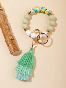 Close-up of tropical bird print silicone beads and green layered tassel on key ring