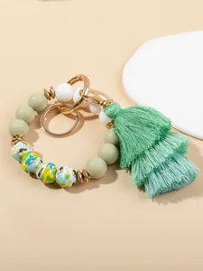 Detail of sage green silicone bead keychain with floral patterns and silk tassel fringe