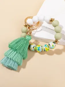 Detail of beaded keychain bracelet with silicone beads and green gradient tassel charm