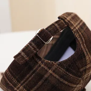 Close-up of brown plaid wool baseball cap with adjustable metal buckle and stitching