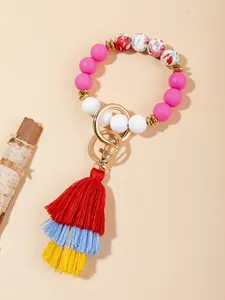 Detail of colorful silicone beaded bracelet with tassel and gold metal ring clasp