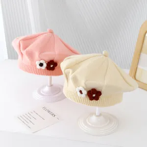 Close-up of pink and beige knitted baby berets with decorative handmade wool flowers