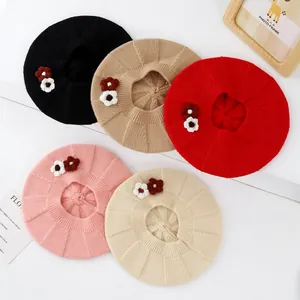 Detailed knit texture of children's berets with crochet floral accents in five colors