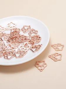Vue macro de breloques en forme de patte ajourée or rose pour création de bijoux