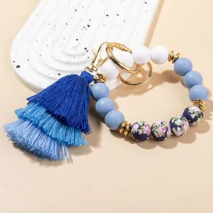 Bohemian silicone bead bracelet with blue tassel and gold metal carabiner on warm background