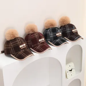 Detail view of plaid winter kids baseball caps with fur pompom and Boston leather patch