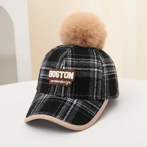 Detail of plaid winter baseball cap with faux fur pompom and embroidered Boston logo