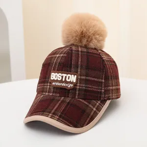Detail of plaid winter baseball cap with faux fur pom-pom and Boston embroidered patch