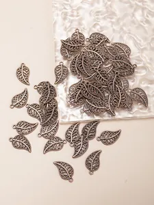 Detailed macro of antique bronze hollow leaf charms with intricate filigree texture
