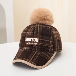 Detail view of winter plaid baseball cap with BOSTON embroidery and large faux fur pompom
