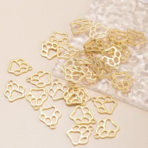 Pendentifs pattes ajourés dorés pour bracelets DIY, dispersés sur fond beige clair