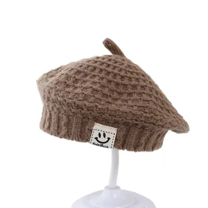 Winter brown knitted baby beret with a smiling face label and cute waffle texture