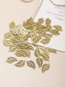 Detailed view of vintage bronze filigree leaf charms with loops for DIY jewelry making