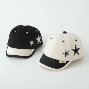 Detail der Kontrast-Sternstickerei und Markenlabels auf Baumwoll-Baseballkappen für Kinder
